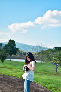 Side view of woman standing on field against sky