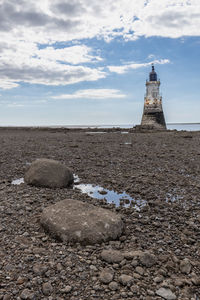 Rocks on beach by sea against sky