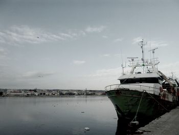 Boats moored at harbor against sky