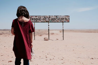 Rear view of woman standing on road