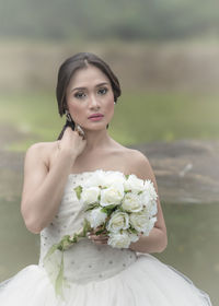 Portrait of beautiful bride holding white roses bouquet