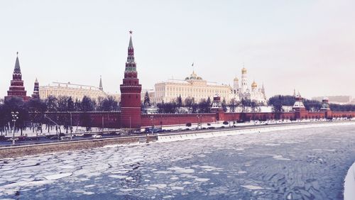 Scenic view of frozen lake by city against clear sky