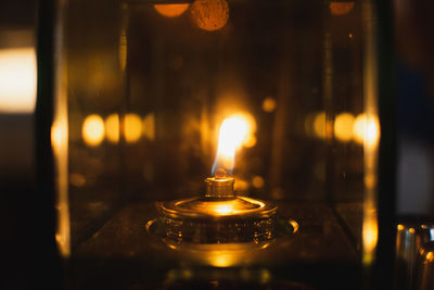 Close-up of illuminated candles on glass table