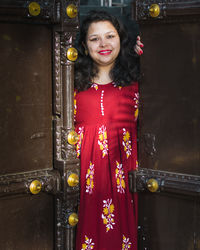 Portrait of smiling woman standing at entrance