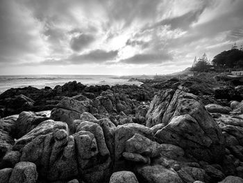 Scenic view of rocks by sea against sky