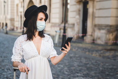 Full length of woman using mobile phone in alley