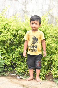 Portrait of boy standing against plants