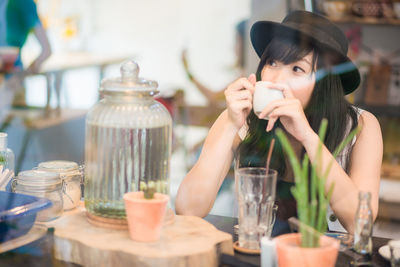 Portrait of young woman drinking glasses on table at cafe