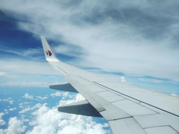 Cropped image of airplane flying over cloudscape against sky