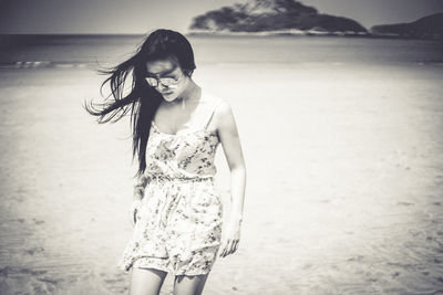 Woman in sunglass standing at sandy beach