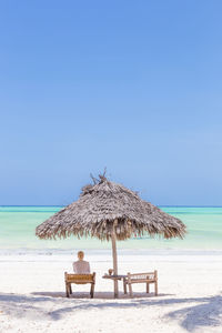 Lifeguard hut on beach against clear blue sky