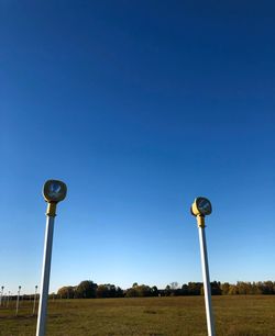 Street light on field against clear blue sky