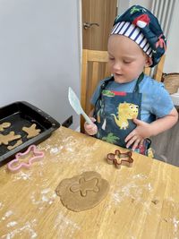 Young boy making gingerbread men with dough