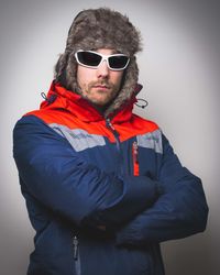 Young man wearing sunglasses standing against white background