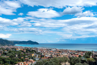 Aerial view of townscape by sea against sky