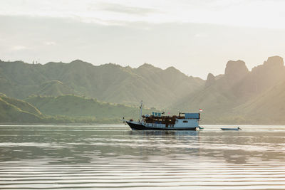 Boat sailing on sea against mountains