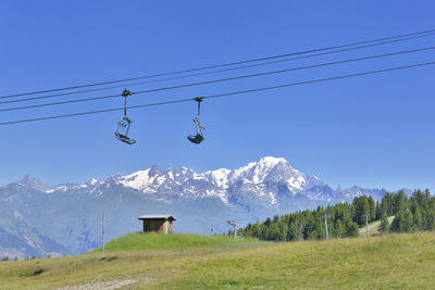 Overhead cable car on snowcapped mountains against clear sky