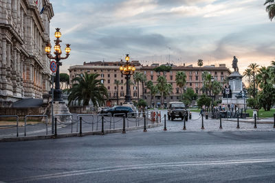 View of city street against cloudy sky during sunset