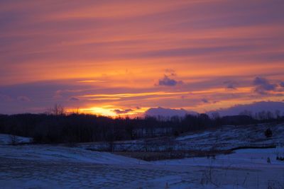 Winter landscape against sky during sunset