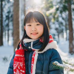 The joy of the winter. portrait of smiling young girl in a snowcapped forest, wearing warm clothes.