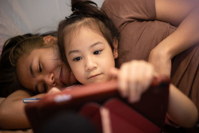 Asian mom and adorable daughter are laying on the floor in house with happy and joyful moment 