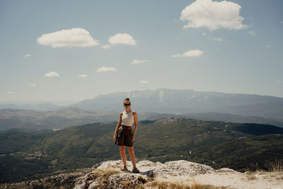 Rear view of man standing on mountain against sky