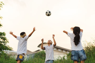 People playing soccer on field against sky