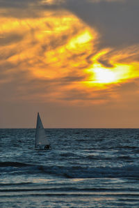 Sailboat sailing on sea against sky during sunset