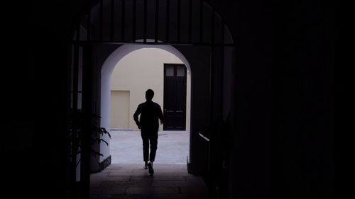 Rear view of silhouette man standing at entrance of building