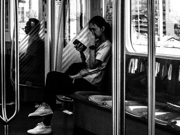 Rear view of woman sitting on train window