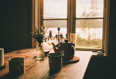 Crockery and flowers in vase on table at home