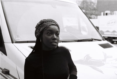 Close-up of young woman against car