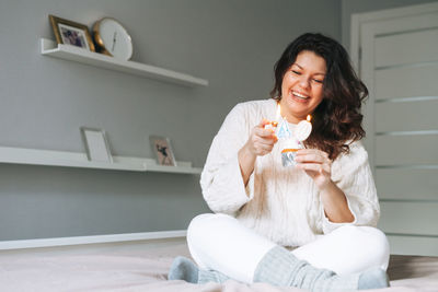 Young adult woman forty years plus size body positive in sweater with festive cupcake with candle 