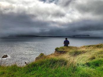 Rear view of man looking at sea against sky