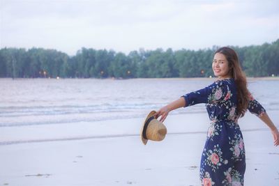 Portrait of smiling young woman standing on the beach