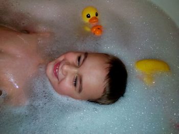 High angle view of shirtless smiling boy in bathtub