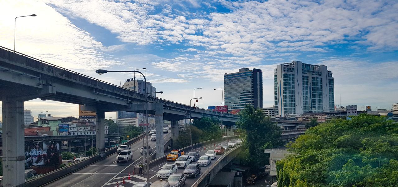 VEHICLES ON ROAD AGAINST CLOUDY SKY