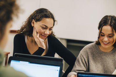 Smiling teenage students studying in classroom