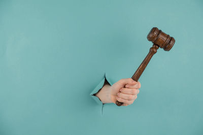 Woman's hand holding a wooden judge's gavel on a blue background