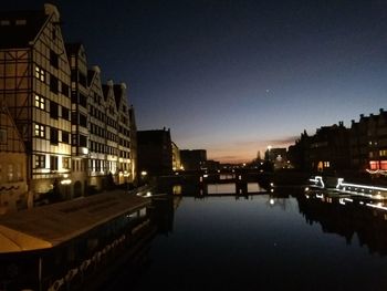 River by illuminated buildings against sky at night