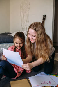 Two girls friends play at home, draw with pencils and felt-tip pens and have fun