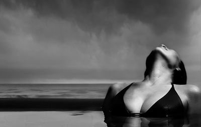 Close-up of sensuous woman in infinity pool against sea