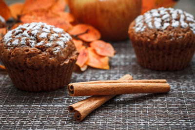 Chocolate muffins with apple filling on a background of autumn leaves and cinnamon