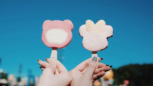 Close-up of hands holding heart shape against blue sky