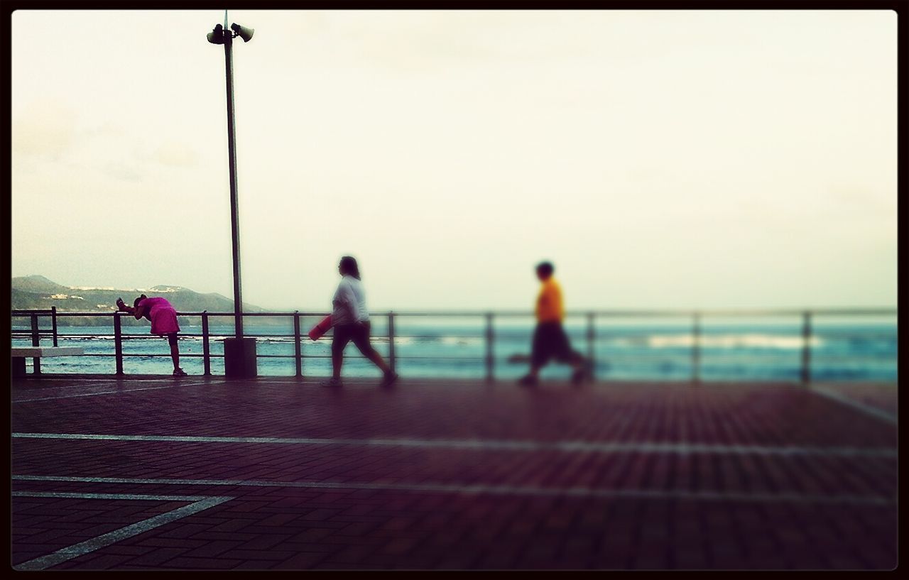 sea, transfer print, railing, men, horizon over water, lifestyles, leisure activity, water, clear sky, sky, auto post production filter, person, rear view, pier, standing, copy space, beach, full length