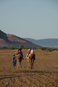 Man riding horse on desert against clear sky