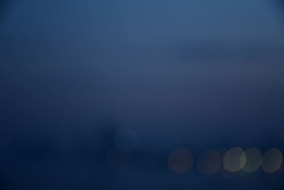 Low angle view of defocused lights against sky at night