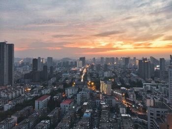 High angle view of illuminated cityscape against cloudy sky