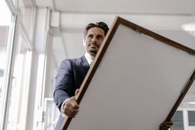 Smiling businessman holding picture frame