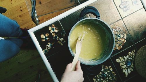 Cropped hand preparing food in utensil at kitchen